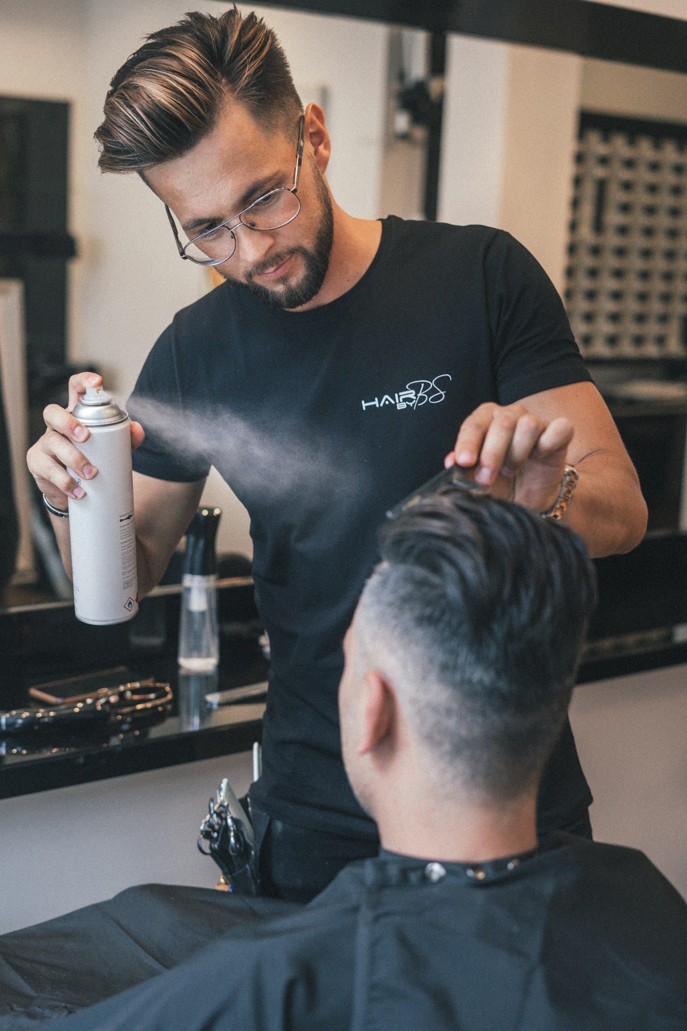 Barbeiro finalizando o penteado com spray (foto ilustrativa)